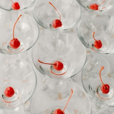 Refreshing alcoholic drinks with cherries served on white table